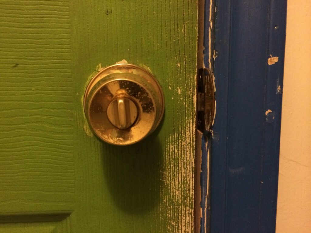 Gold Knobset Lock on a Green Door with a Blue Doorframe