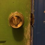 Gold Knobset Lock on a Green Door with a Blue Doorframe